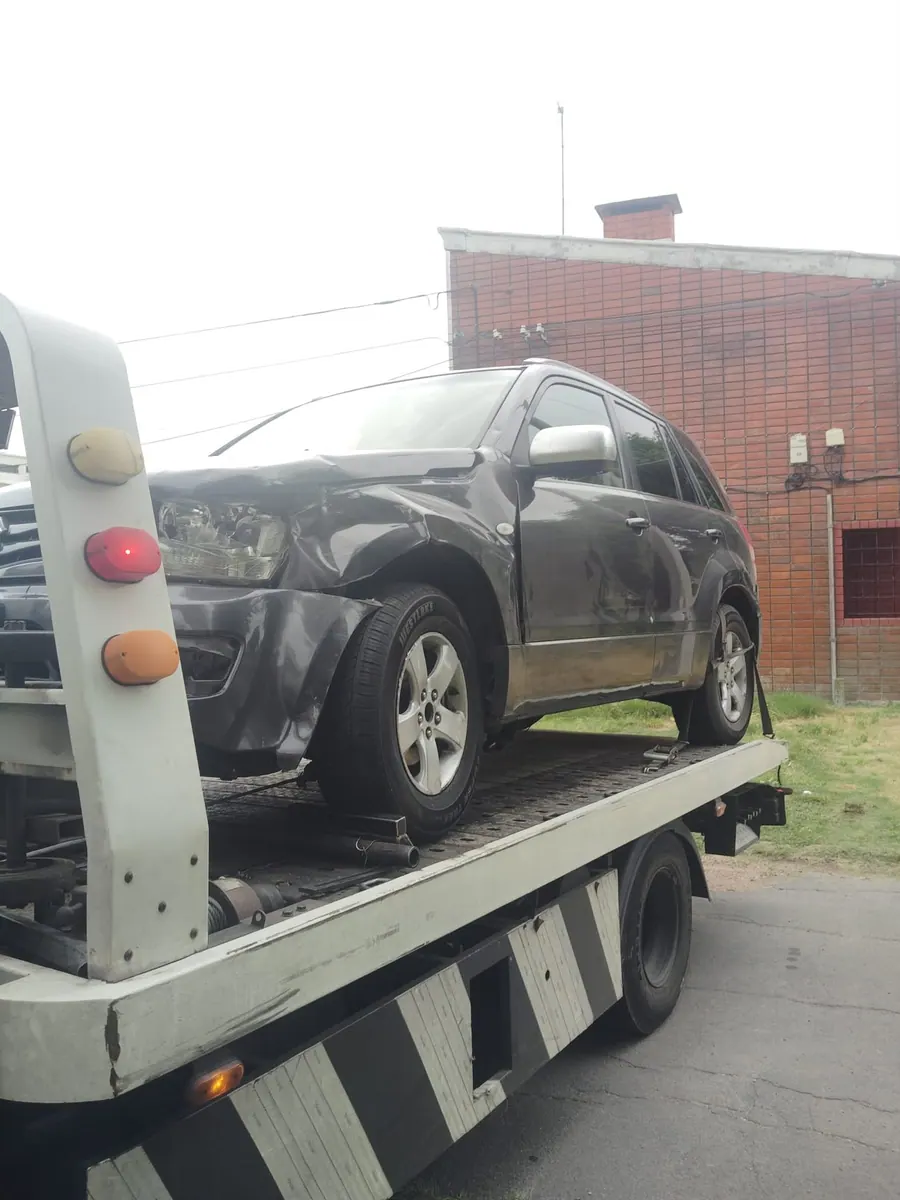 Traslado de una SUV oscura con daños frontales sobre plataforma